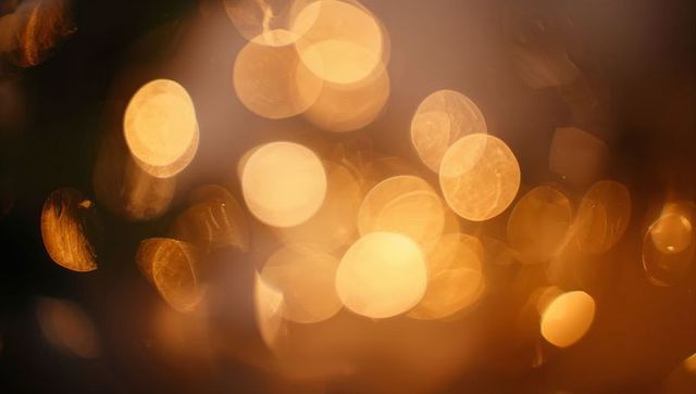Warm golden bokeh lights abstract background with soft glowing orbs and lens flare