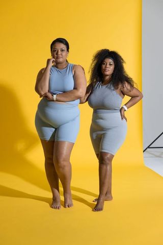 Curvy models posing in matching athleisure on vibrant yellow studio backdrop