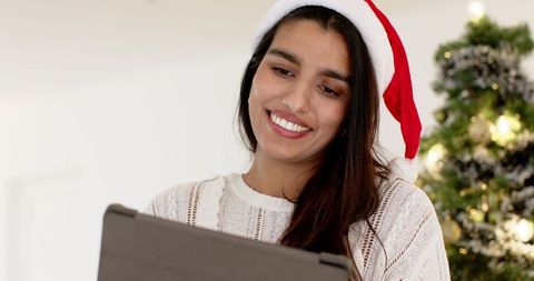 Festive Woman with Santa Hat Enjoying Tablet Amid Christmas Season