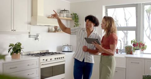 Young Couple Inspecting Modern Kitchen Stove and Shelves
