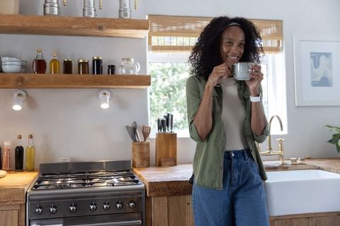 African american woman smiling while sipping coffee in cozy farmhouse kitchen morning