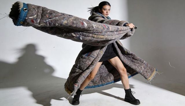 Dynamic spin showcasing oversized quilted coat with blue trim, dramatic motion and shadow