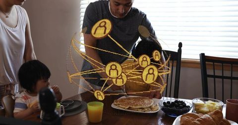 Parents serving pancakes to children at breakfast table with augmented reality overlay
