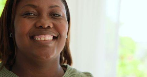 African American Woman Smiling Indoors By Sunlit Window