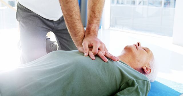 A senior man is receiving a chest examination or treatment from a healthcare professional, a doctor or a physiotherapist, with copy space. It illustrates the importance of medical care for the elderly to maintain their health and well-being.
