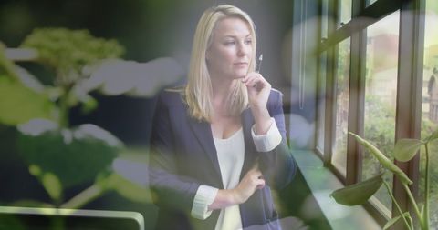 Confident businesswoman daydreaming at bright office window