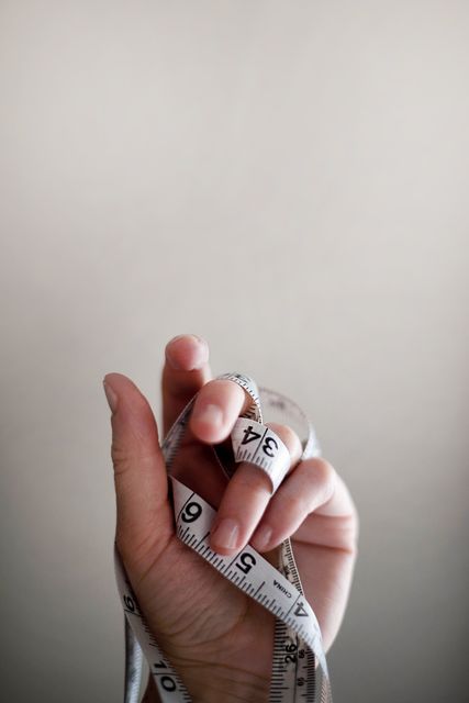 Hand holding measuring tape offers themes of precision and preparation. Suitable for use in articles about DIY projects, sewing, tailoring, construction, and crafts. Good for blogs and content covering measurement tools, home improvement, or professional skills involving accuracy and attention to detail.