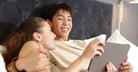 Couple relaxing in bed watching tablet, intimate cozy moment with technology