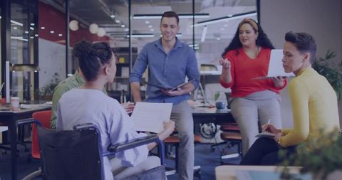 Diverse team discussing project in modern open office with wheelchair inclusion