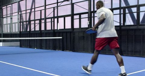 Athletic Man Playing Paddle Tennis in Indoor Sports Court