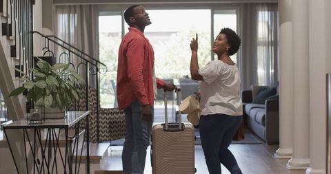 Joyful african american couple returning home with luggage