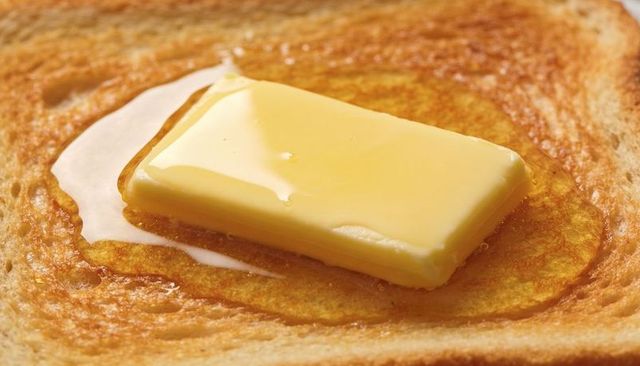 Melting butter pat on golden toast closeup with glossy melted pool