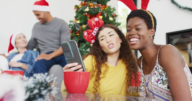 Happy group of diverse friends taking selfies at christmas party. Spending quality time at home together at christmas.