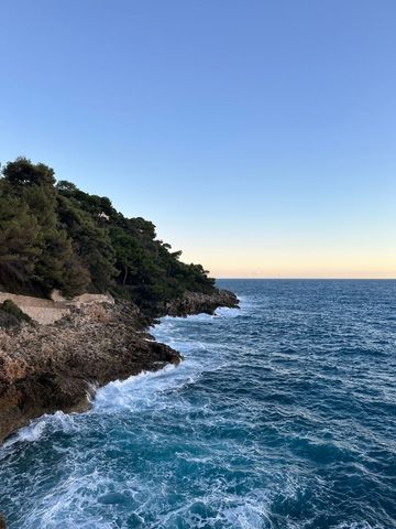 Scenic view of rocky beach coastline with turquoise sea and clear sky