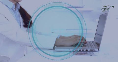 Clinician typing on laptop with HUD overlay in minimalist blue healthcare workspace