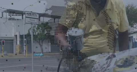 Tradesman holding spray gun and examining paper through perforated mesh on street