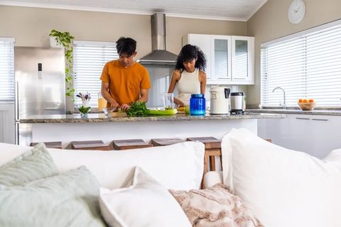 Young asian man and african american woman chopping greens on granite kitchen island