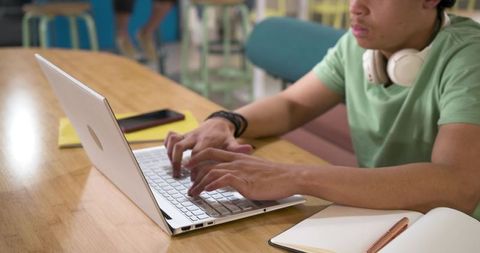Focused African American Student Typing on Laptop in Coworking Space with Notebook