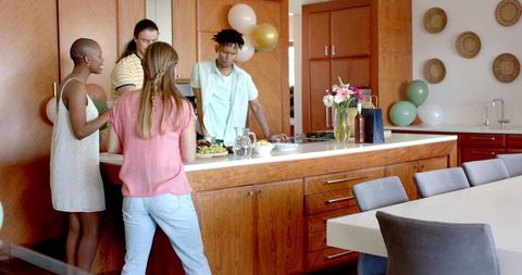 Friends Gather in Kitchen Sharing Food and Smiles at Party