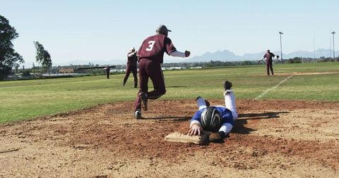 Intense Baseball Game with Players Sprinting and Sliding into Base