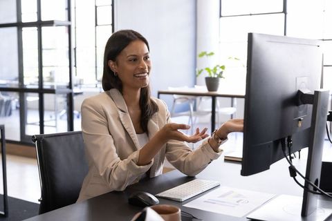 African American businesswoman smiling and gesturing at monitor during virtual meeting