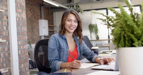 Smiling Businesswoman Writing Notes in Modern Office