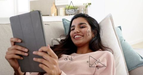 Relaxing indian woman using tablet on couch with math doodles and geometry diagrams