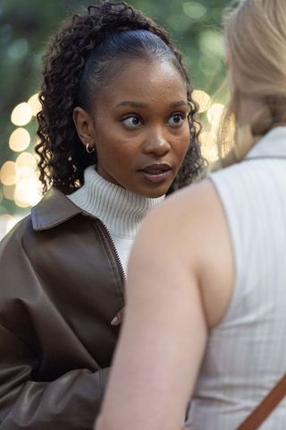 Intense outdoor conversation between diverse women at dusk with warm bokeh lights and leather jacket