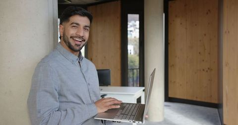 Business Professional Smiling with Laptop in Modern Office