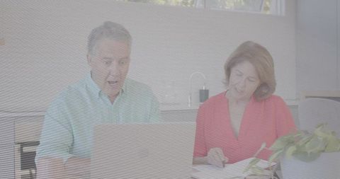 Senior couple managing finances, comparing bills and using laptop in modern kitchen
