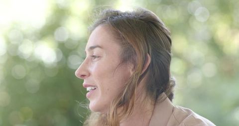 Profile portrait of woman speaking softly in garden with bokeh light and calm expression