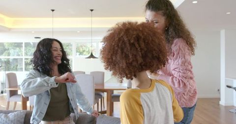 Diverse friends laughing and fist-bumping in modern open-plan living room