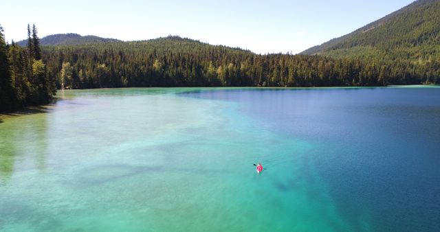 Person Kayaking on Stunning Crystal Clear Lake Amidst Forested Mountains - Download Free Stock Images Pikwizard.com