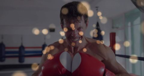 Muscular boxer training with red gloves in ring showing determination, focus and intensity