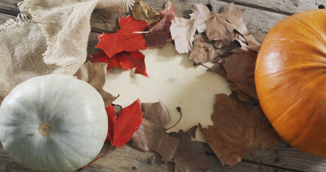 Autumn pumpkins and leaves positioned on a rustic wooden table. This image can be used for themes such as fall decor, seasonal changes, nature, and harvest festivals. Suitable for blog posts, social media, greeting cards, and marketing materials centered around the autumn season.