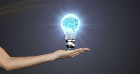 Innovative brain inside light bulb hovering over hand