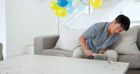 Man Cleaning Living Room Before Celebration with Balloons