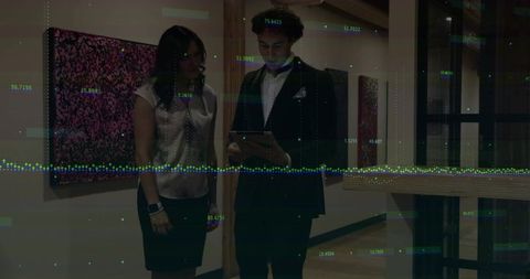 Business colleagues reviewing tablet with digital data overlay in art gallery corridor