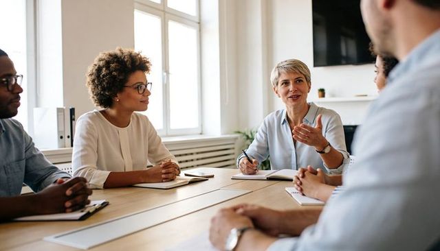 Professional team meeting with woman leader facilitating discussion at modern office table