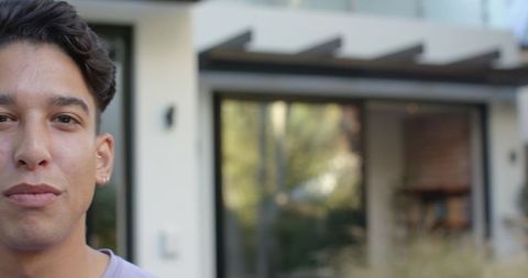 Man standing outside modern home with reflective glass door