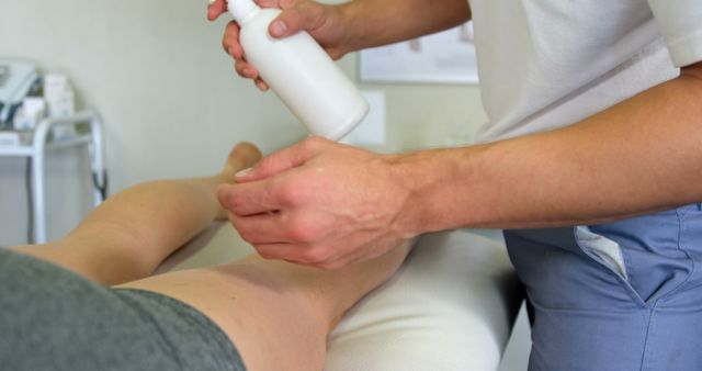 Physiotherapist applying lotion to female patient in clinic