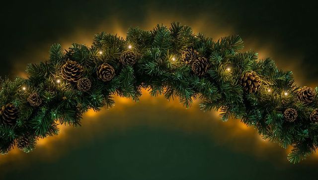 Evergreen garland arching with pine cones and warm white lights creating festive glow