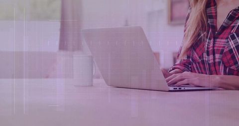 Woman in checkered shirt working on laptop at home office