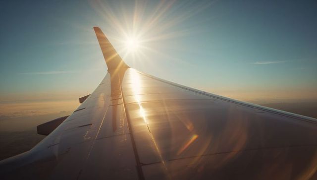 Airplane Wing Gliding Through Sunrise Skies Above Clouds