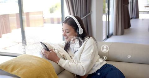 Listening to music and browsing smartphone on sofa with social network overlay