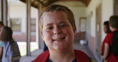 Smiling schoolboy in corridor enjoying school