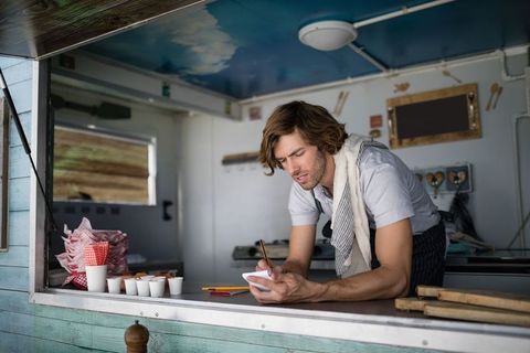 Food truck vendor writing order at vintage mobile kitchen