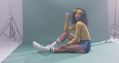 Retro summer studio fashion model wearing mustard top denim shorts visor and striped socks