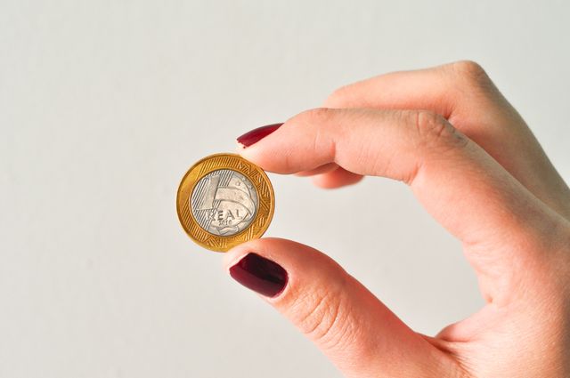 Close-up of Woman Hand holding a coin against white background. Finance, economy and currency concept 
