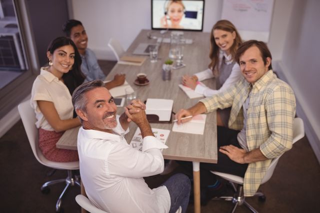 Portrait of smiling business people attending video conference meeting in office